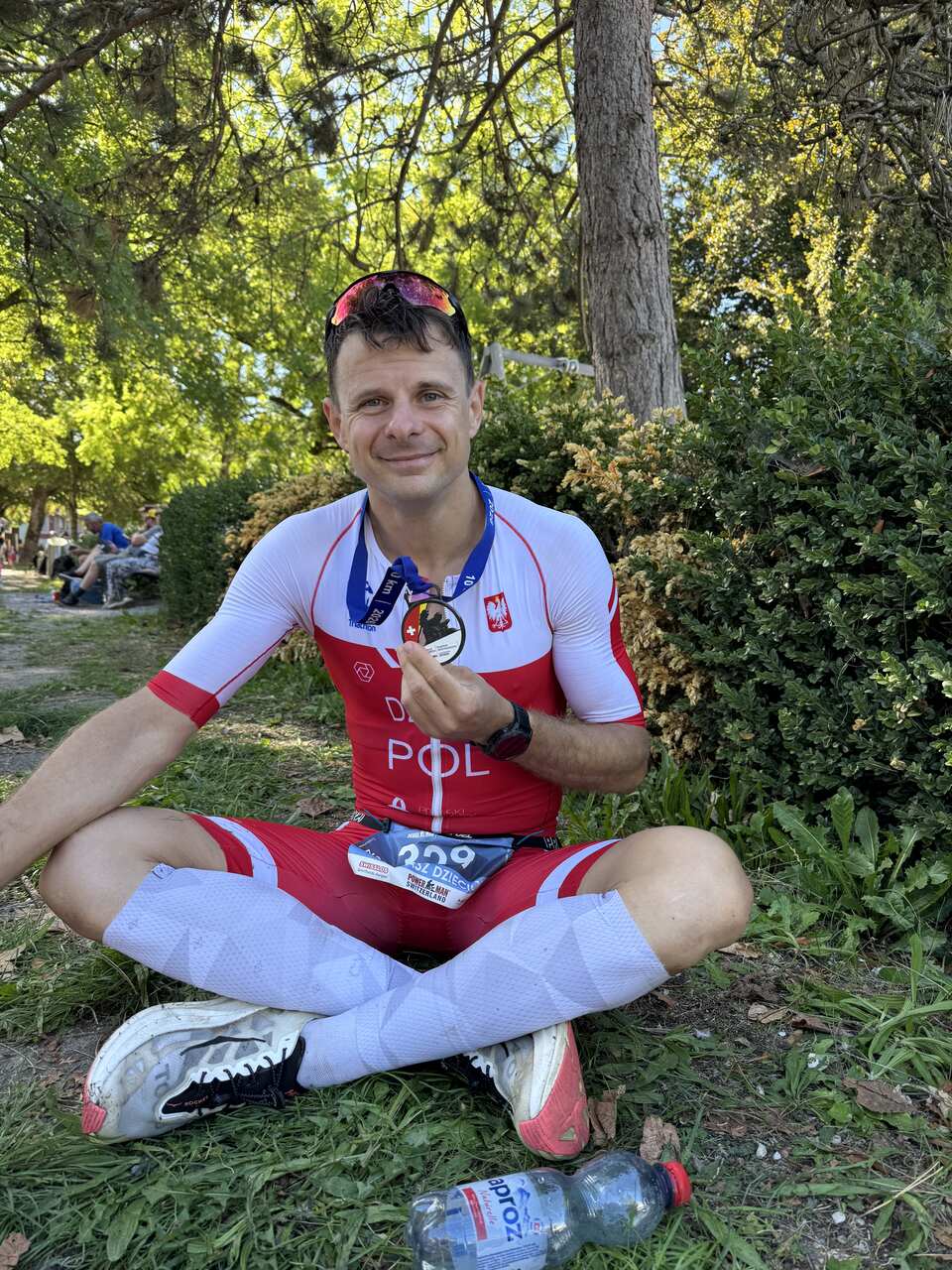 Tomek siedzi na trawie z medalem mistrzostw świata Powerman Zofingen 2026